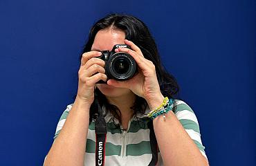 Een collega richt een Canon-camera recht naar voren terwijl ze een foto maakt.