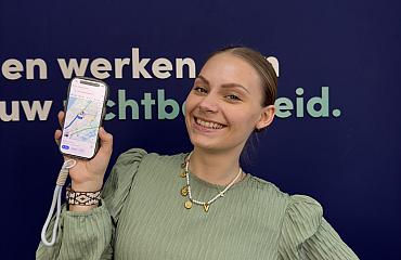 Vrouw houdt smartphone met kaartweergave vast en glimlacht tegen blauwe achtergrond met tekst over zichtbaarheid.