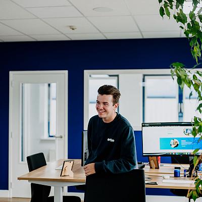 Man die lachend voor zijn bureau staat