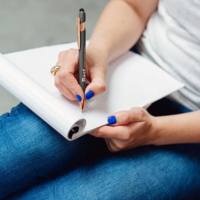 Close-up van een vrouw die met een pen van Best Marketingbureau in een notitieblok schrijft, met blauwe nagellak en spijkerbroek.