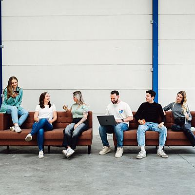 Beeldscherm met het ontwerp van het logo van Best Marketingbureau in Adobe Illustrator, met op de achtergrond een vrouw die op kantoor aan haar bureau zit.