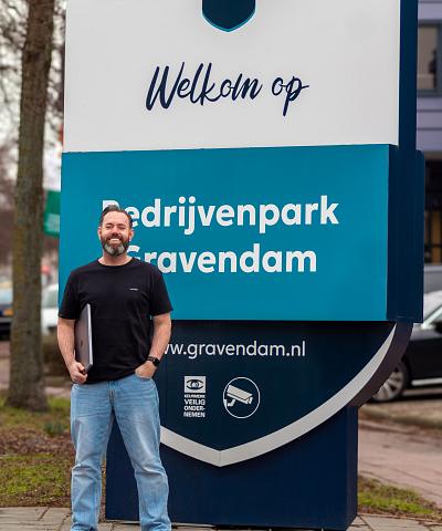 Twee collega’s die samen aan het werk zijn in een licht kantoor met grote ramen, waarbij een van hen lachend naar de camera kijkt.