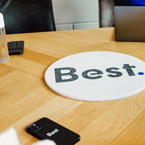 Best logo plat op een houten tafel met laptop op de achtergrond.