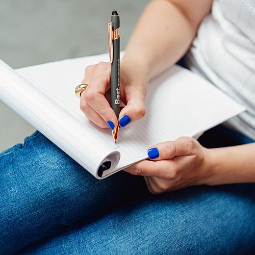 Hand die pen vasthoudt en iets schrijft op blad van notitieblok.