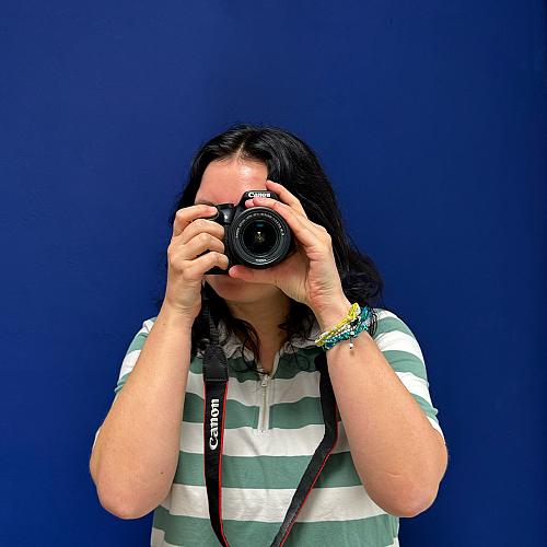 Een collega richt een Canon-camera recht naar voren terwijl ze een foto maakt.