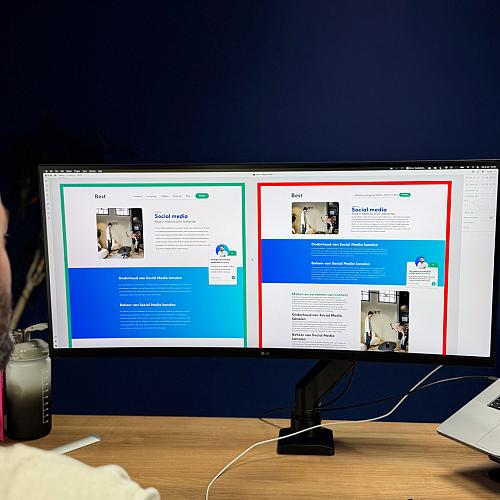 Een man bekijkt twee webdesigns naast elkaar op een ultrabrede monitor in een kantooromgeving.