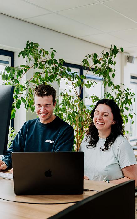 Man en vrouw kijkend lachend naar hun laptop
