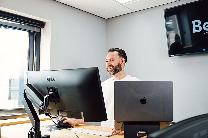 Man werkt achter een computerscherm op kantoor en kijkt geconcentreerd naar zijn monitor.