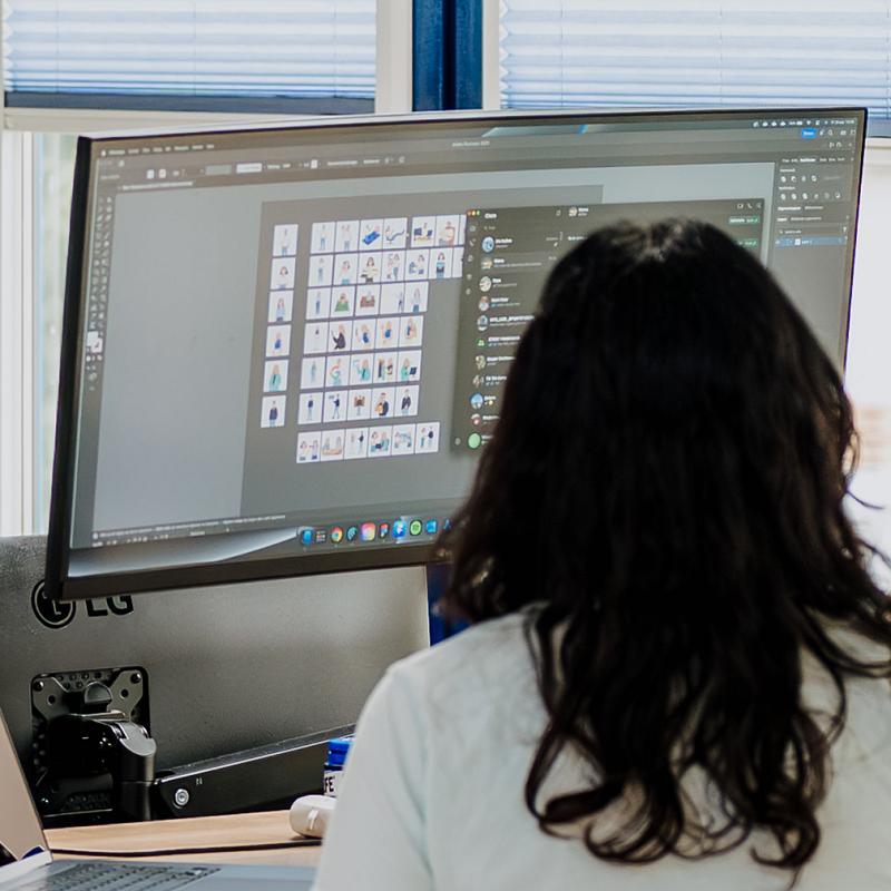 Persoon werkt op een groot beeldscherm aan digitale illustraties en grafisch ontwerp.