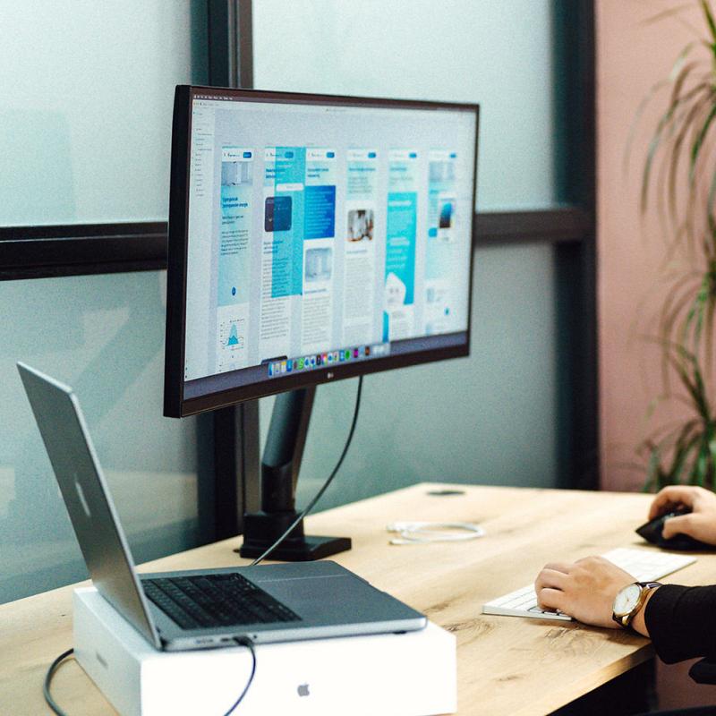 Persoon werkt aan een computerscherm met het ontwerp van een website-interface.