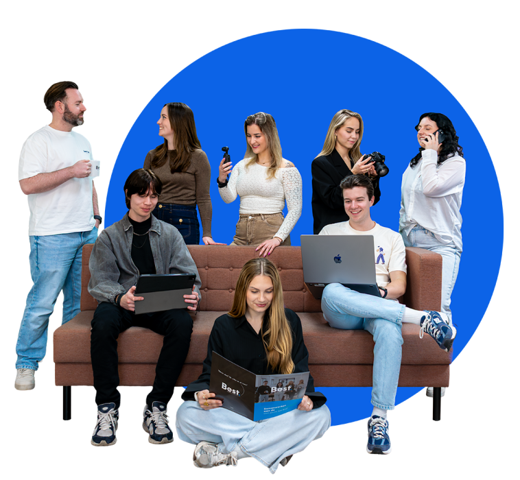 Groepsfoto van acht collega’s die met elkaar praten en lachen rond een bruine bank, met een blauwe cirkel op de achtergrond.